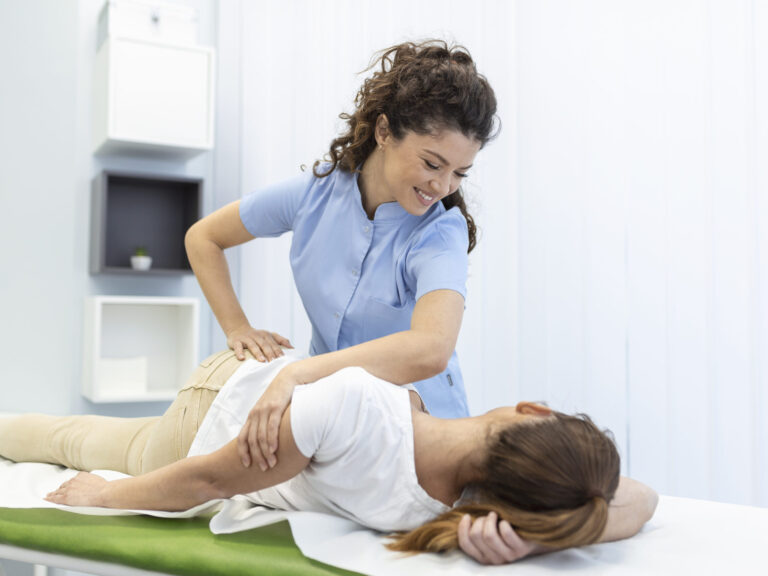 Young woman doctor chiropractor or osteopath fixing lying womans back with hands movements during visit in manual therapy clinic. Professional chiropractor during work